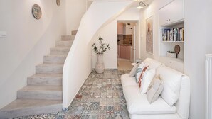 Ein Flur mit weißer Treppe, einem weißen Sofa und einem gefliesten Boden.