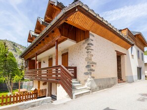 Ein traditionelles Chalet mit Holzfassade, Steinstufen und einer Holzterrasse.