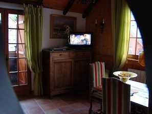 Ein Holzinterieur mit einem Fernseher auf einem Schrank, einem gestreiften Sessel und einem Tisch mit einer Schüssel.