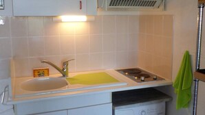 Una cocina con un lavamanos, un escurreplatos, una lavadora y una toalla colgada.