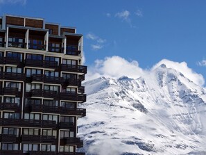 Ein mehrstöckiges Hotel mit Balkonen und Blick auf einen schneebedeckten Berg.