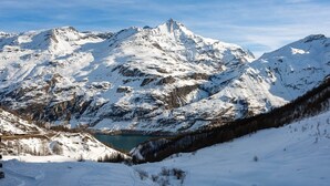 Eine verschneite Berglandschaft mit klarem See und einer kurvenreichen Straße.