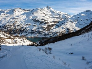 A snow-covered mountain landscape with a clear lake and a winding road. - Tignes Apt for 8 - 3 Rooms, WIFI, Parking (Tignes)