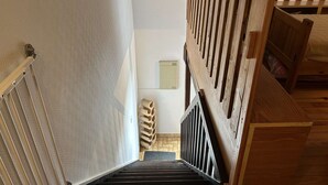 A staircase with wooden steps and a metal railing, leading to a room with a bed and a wooden headboard. - Seaside house 3 rooms, terrace, pets allowed (Fleury-Saint-Pierre-la-Mer)