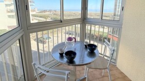 Een balkon met een tafel en stoelen, met uitzicht op de kust.