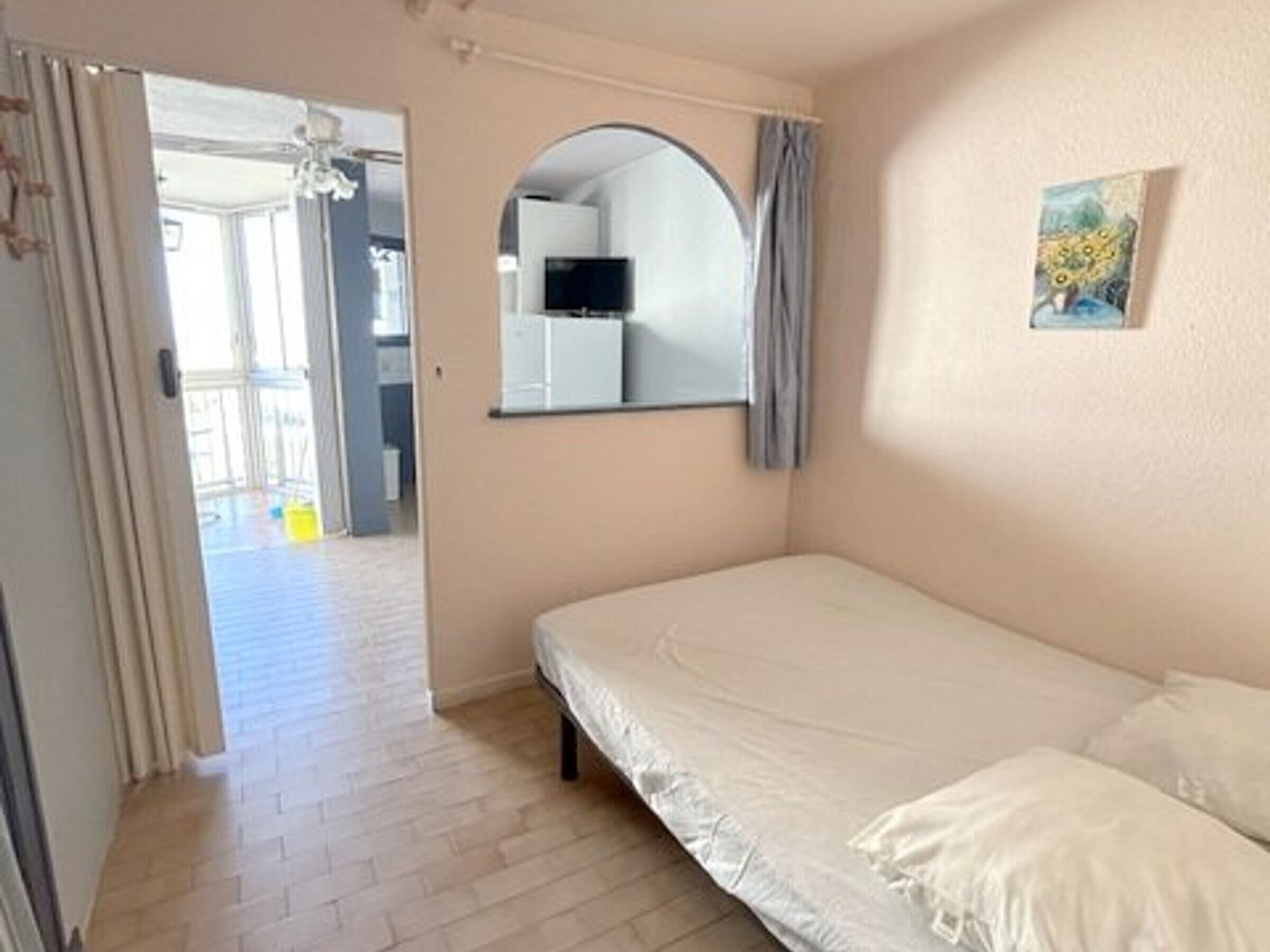 A bedroom with a single bed, a mirror, and a painting on the wall.