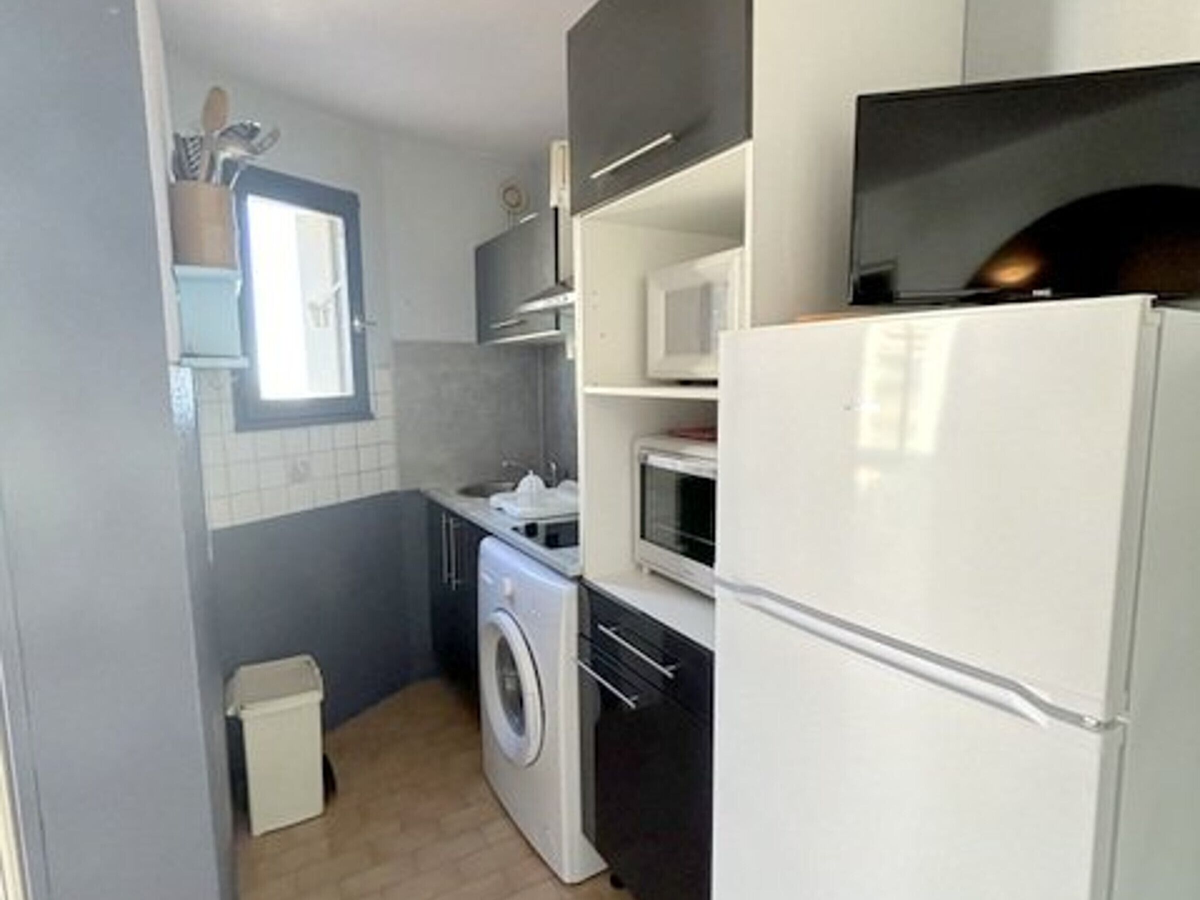 Une cuisine compacte équipée d’un lave-linge, d’un four à micro-ondes et d’un réfrigérateur.