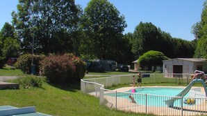 A residential outdoor area with a swimming pool, a tennis court, and a fenced yard. - 30m² Chalet with Terrace for 6 People (Capvern)