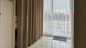 Una habitación con puerta corrediza de vidrio, electrodoméstico blanco y suelo de baldosas.