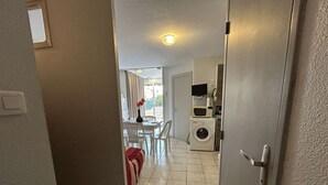 Un pasillo que conduce a un comedor con una mesa y sillas, una lavadora y un microondas.