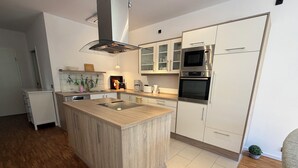 Una cocina moderna con una isla central, electrodomésticos de acero inoxidable y armarios blancos.