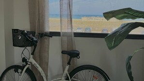 Una bicicleta apoyada en una ventana con vistas a la playa y un estacionamiento.