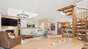 Uma sala de estar moderna com lareira, sofá e uma mesa de jantar de madeira com velas.