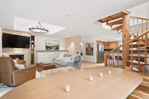 A modern living room with a fireplace, sofa, and a wooden dining table with candles. - Dolomite 11 | 5-Bedroom Aspen Townhome | 4 Levels | Steps from Lift 1A on Aspen Mountain (Aspen)