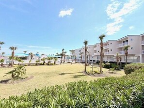 A resort with a central grassy area, palm trees, and multi-story buildings with balconies. - Summer & July 4th Savings at Beachside Colony Tybee's ONLY Oceanfront Resort 2/2 (Tybee Island)