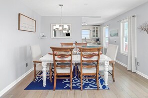 A dining area with a white table, wooden chairs, and a blue rug. - Mexico Beach w/Low Speed Vehicle (Mexico Beach)