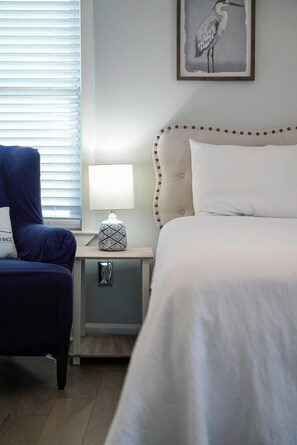 A bedroom with a bed, a nightstand, a lamp, a chair, and a wall-mounted artwork. - Mexico Beach w/Low Speed Vehicle (Mexico Beach)