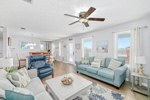 A spacious living room with a blue sofa, a white coffee table, and a ceiling fan. - Mexico Beach w/Low Speed Vehicle (Mexico Beach)