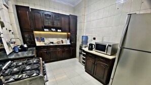 Una cocina con armarios de madera oscura, un refrigerador de acero inoxidable, un microondas y una estufa a gas.