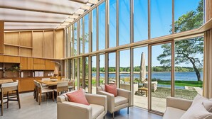 Amplia sala de estar con un gran ventanal, muebles de madera y vista a un lago.