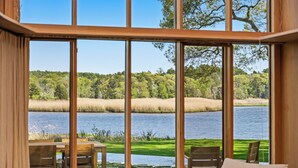 Una habitación con un ventanal grande que da a un lago y un bosque.