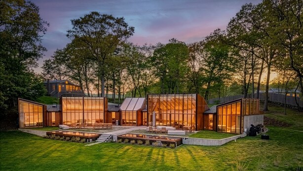 Una casa moderna con amplios ventanales de vidrio, un césped cuidado y un sendero de piedra.