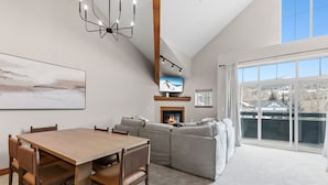 A modern living room with a dining table, sofa, and fireplace. - Spacious Family-Friendly Condo With Updated Finishes (Frisco)