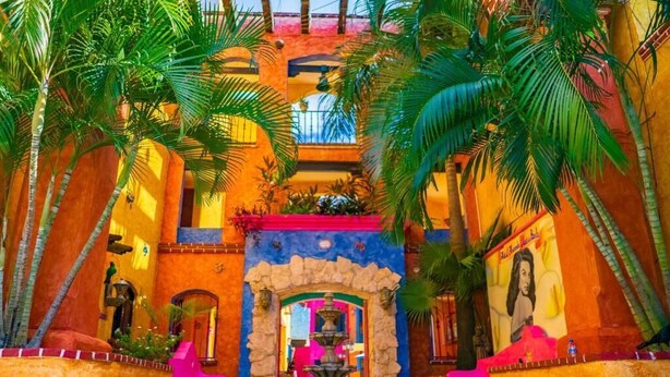 A vibrant courtyard with a fountain, palm trees, and colorful walls. - Hotel Hacienda Maria Bonita (Playa del Carmen)