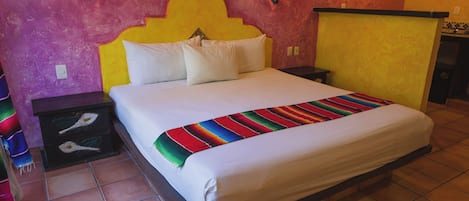 A bed with a colorful blanket, a headboard, and two wall-mounted lights.