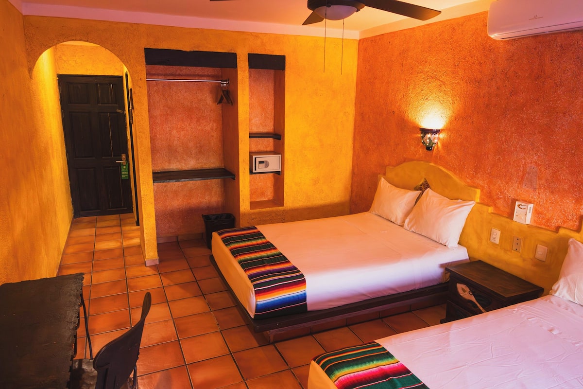 A hotel room with two beds, a shower, and a small table.