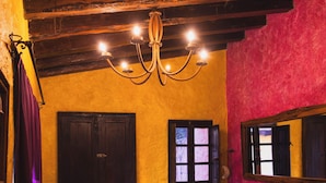 A cozy room with a wooden ceiling, a dark door, a bench, and a sofa with patterned cushions. - Hotel Hacienda Maria Bonita (Playa del Carmen)