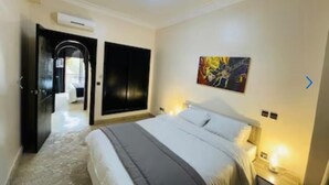 A hotel room with a large bed, a painting on the wall, and a door leading to another room. - Villa Aria Private heated pool 4 bedrooms (Marrakech)