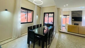 A dining area with a glass table and chairs, a sofa, and a view of the outside. - Villa Aria Private heated pool 4 bedrooms (Marrakech)