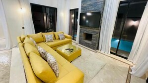 A modern living room with a yellow sofa, a flat-screen TV, and a fireplace. - Villa Aria Private heated pool 4 bedrooms (Marrakech)