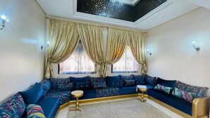A living room with a blue sofa set, a chandelier, and a patterned ceiling. - Villa Aria Private heated pool 4 bedrooms (Marrakech)