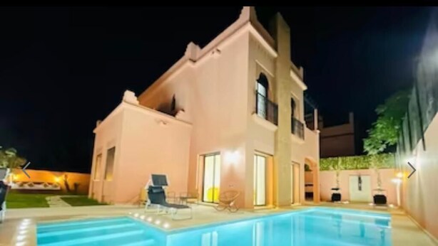 A modern house with a swimming pool, a patio with chairs, and a well-lit entrance. - Villa Aria Private heated pool 4 bedrooms (Marrakech)