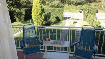 A balcony with two blue chairs and a small table with drinks and snacks.