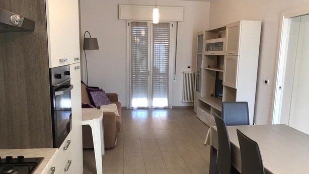 A modern kitchen with a stove, cabinets, and a dining area with a table and chairs. - Sicily house 100 mt from the sea, garden, climate, terrace, laundry room (Cervia)