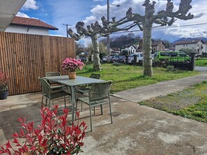 Ein Sitzbereich im Freien mit Tisch und Stühlen, einem Holzzaun und einem Blumentopf.
