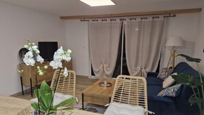 Ein Wohnzimmer mit einer Couch, einem Couchtisch, einem Fernseher und einer Topfpflanze.