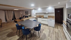 Eine moderne Küche mit weißen Schränken, einer Holz Arbeitsplatte und einem eingebauten Backofen. Es gibt einen Essbereich mit einem Tisch und blauen Stühlen.