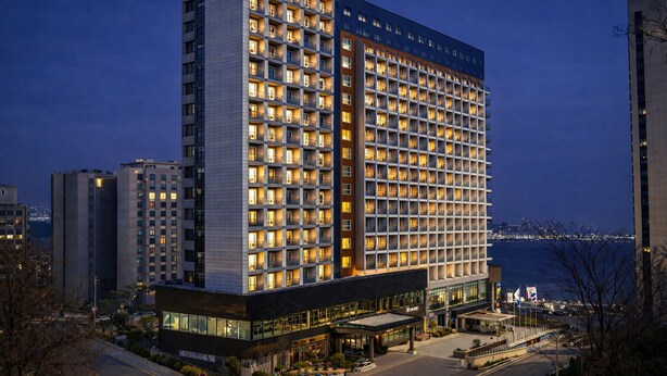 Een hoog hotel met meerdere verdiepingen, een opvallende ingang en een uitzicht op de stadsachtergrond.