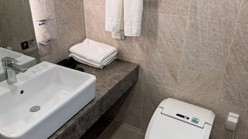 Ein Badezimmer mit einem weißen Waschbecken, einer Toilette und einem Handtuchhalter mit gefalteten Handtüchern.