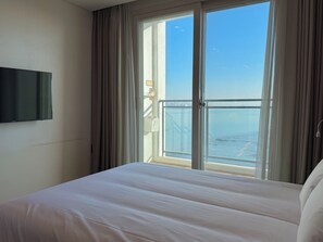 A hotel room with a bed, a TV mounted on the wall, and a large window with curtains. - Sky Stay (Incheon)