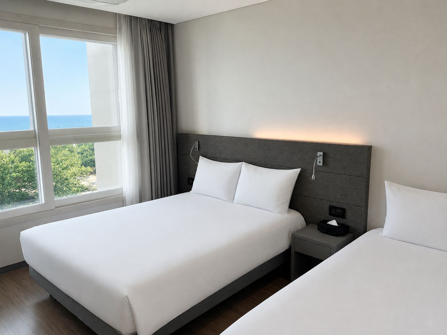 A hotel room with a bed, bedside table, and a view of the sea.