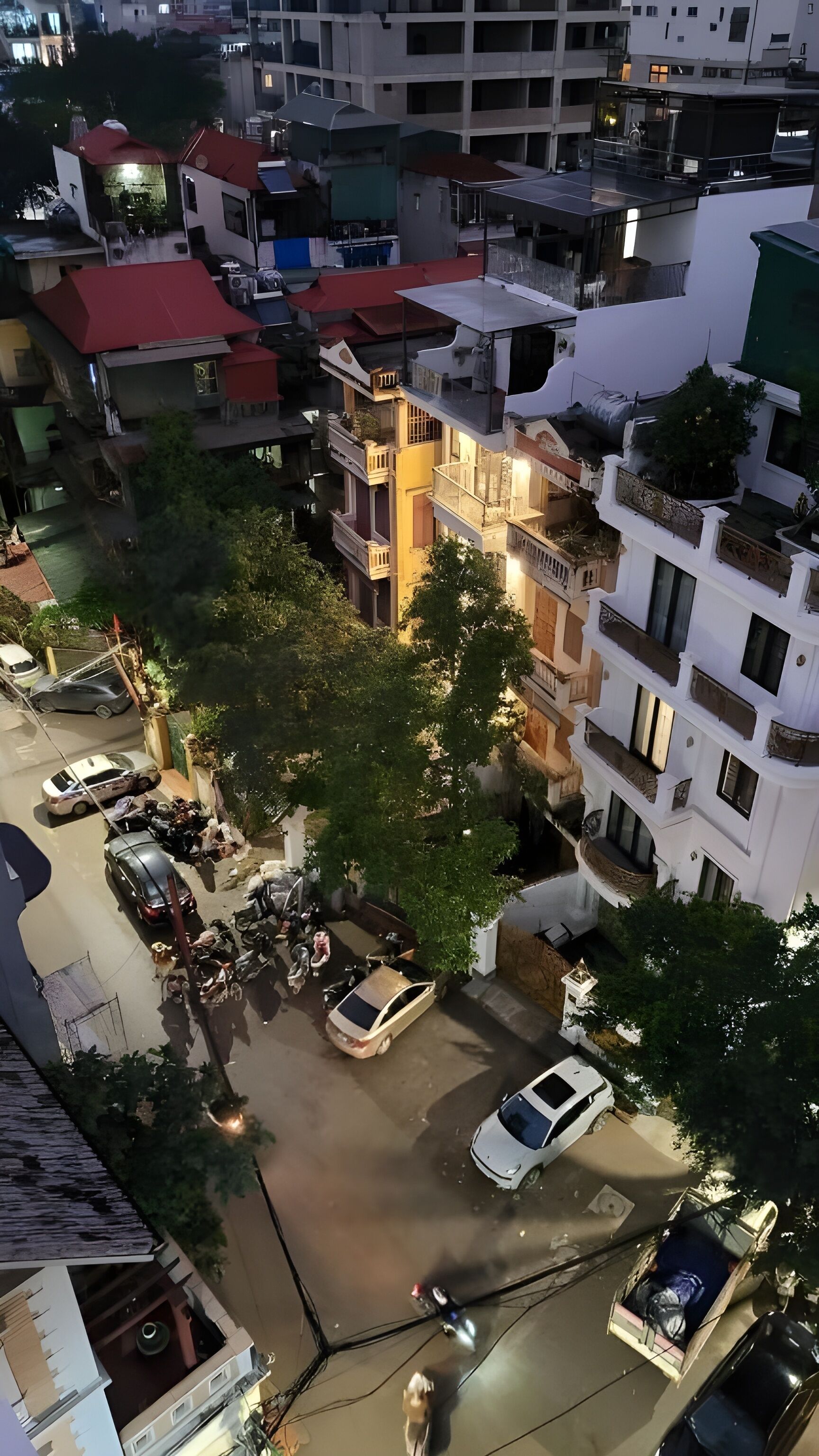 A multi-story building with balconies and a parking area.