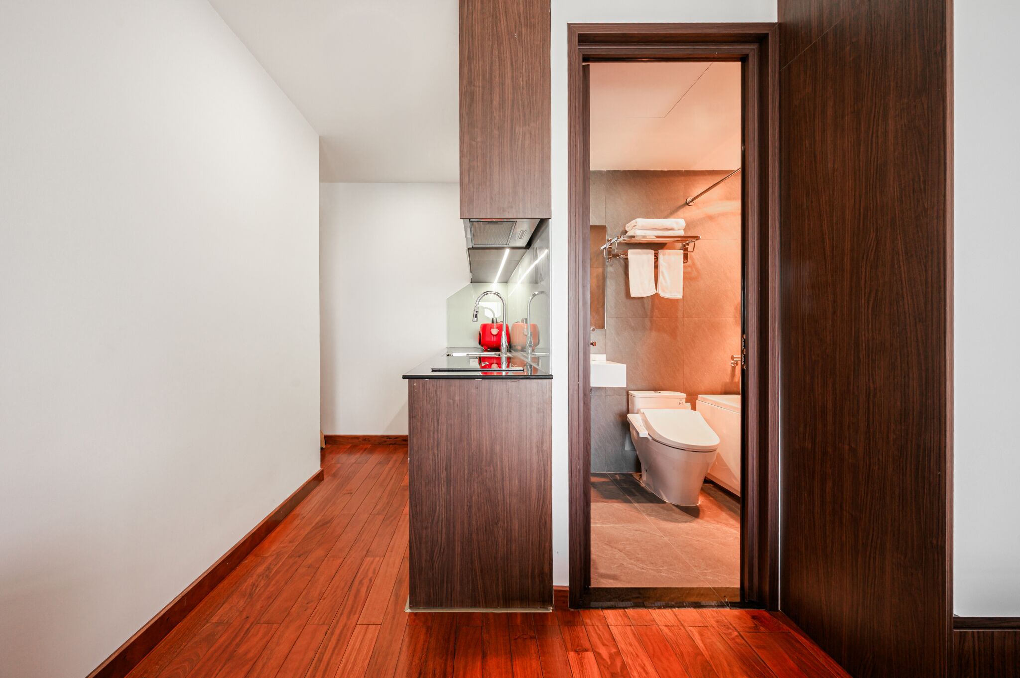 A modern bathroom with a wooden vanity, a toilet, and a towel rack.
