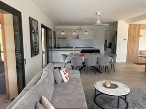 A modern living room with a sofa, a coffee table, and a dining area with chairs and a table. - Recent house surrounded by a natural park (Saint-Jean-de-Laur)