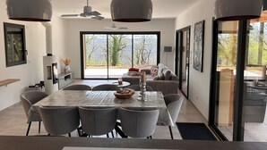 A modern dining area with a large table, grey chairs, and pendant lighting. - Recent house surrounded by a natural park (Saint-Jean-de-Laur)