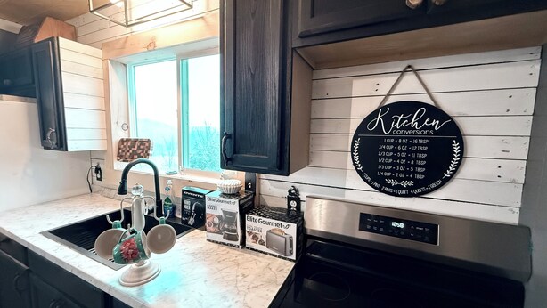 A kitchen with a marble countertop, a coffee maker, a toaster, and a wall-mounted sign with kitchen conversions. - Wolf River Ridge on DHL 
1 minute from boat ramp! 
Kayaks & Bikes included (Byrdstown)